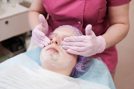 十几岁的女孩在spa沙龙接受美容师的面部护理图片