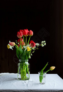 桌上有红色郁金香水仙花和樱花有复制空间和黑色背图片