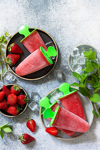 自制草莓冷冻果汁冰淇淋或冰棒放在轻石块或板桌上图片