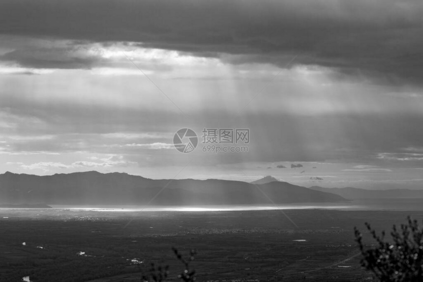太阳射线穿透希腊北部海面的厚云从希腊Xanthi地区山脉的高角度观察黑白旅行照片图片