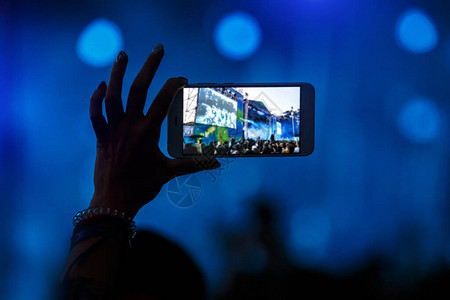 在现场音乐会表演中拍摄照片和录像的手机照图片