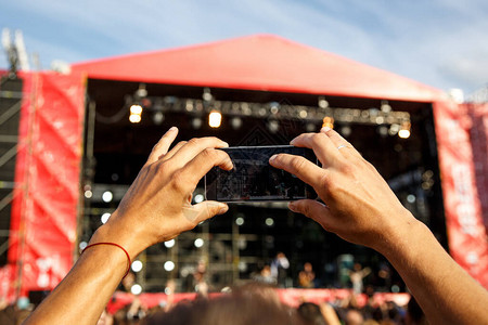 男人手里拿着智能手机和拍照在夏季户外音乐会节的前台拍背景图片