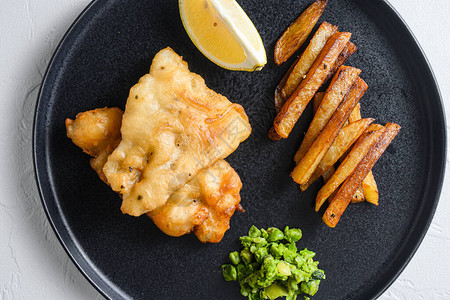 英国传统食物鱼和薯条上面有豆子和柠檬图片
