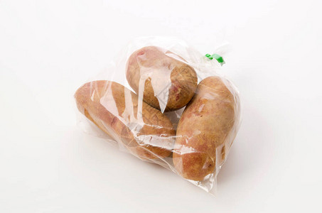 新鲜的红皮土豆白色背景的塑料袋里有土图片