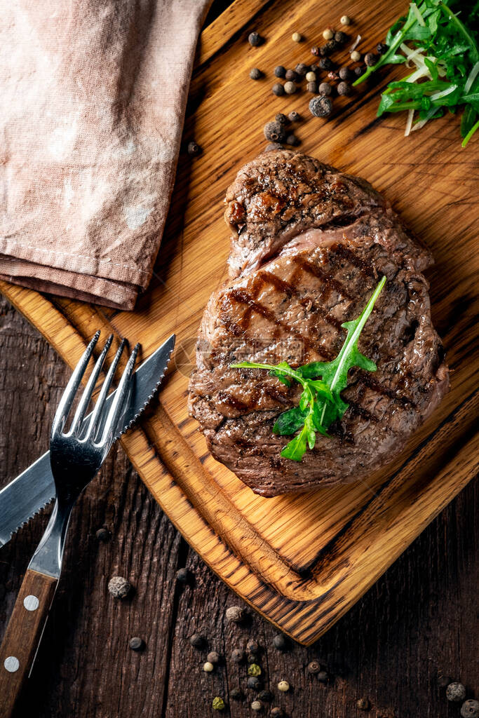 烤夹头牛排配酒刀和叉子在木板上整块烤肉图片