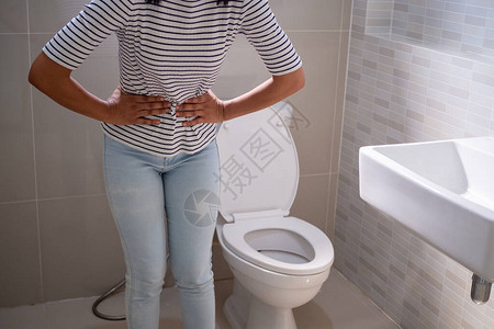 妇女站在厕所的洗手间里图片