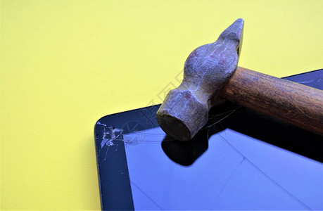 一块破旧木头的旧锤子躺在一块破屏风的平板电脑旁边图片