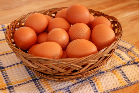 老式桌布上的棕色鸡蛋和篮子里的鸡蛋图片