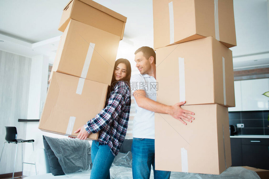 年轻夫妇在新家里携带许多纸板箱一个接一图片