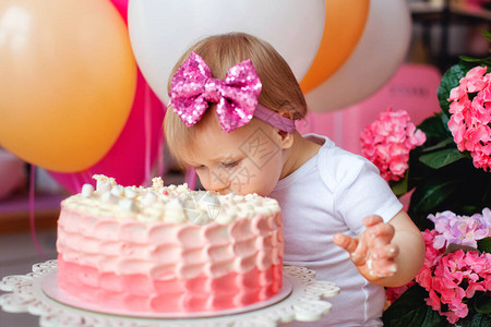 桌子上的一个小女孩拿着生日蛋糕和气球蛋糕的崩溃宝的第一个生图片