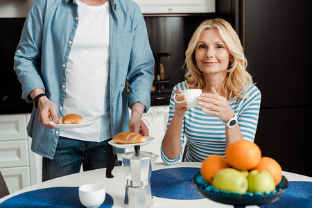有选择焦点微笑的女人与咖啡杯靠近男人在厨房里图片