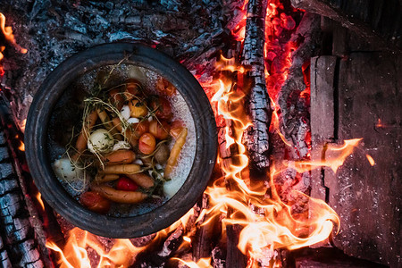 在野营旅行中用柴火顶视图烹饪蔬菜火锅着火了野餐图片
