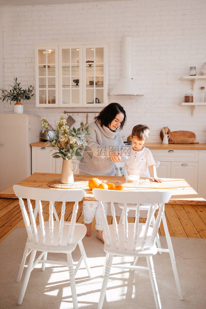 妈和儿子在家里的厨房里用小麦粉准备面粉制品孩子帮助父母做饭面图片