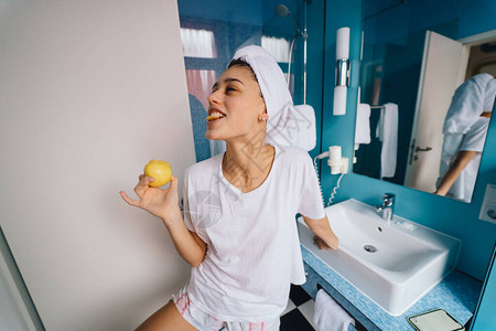 年轻的caucasian女人穿着毛巾在头上和T恤在浴室的浴图片