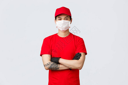 自信的亚洲年轻男子身穿红色送货服务制服和帽子图片