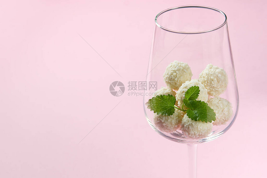 酒杯中的白椰子松露与薄荷叶带有复制空间的粉红色背景中带有椰图片