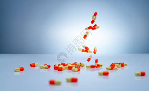 黄橙色胶囊丸落在白色的桌子上医药行业氨甲环酸胶囊丸用于治疗月经过多图片