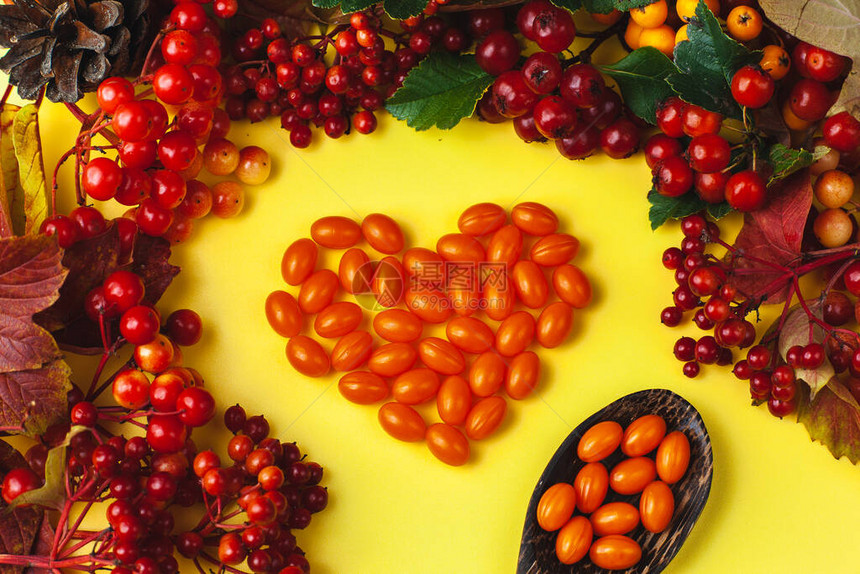 以心脏形式展示的CenzymeQ10药片秋季配有维他命和浆果的成分标图片