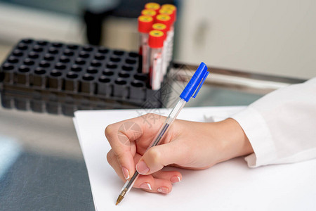 医生的笔写测试结果从实验室用笔在白纸上的病人血液测试管中提取出来图片