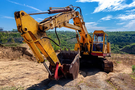 黄色挖掘机在蓝天背景的露天矿坑土方图片