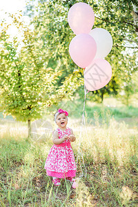 婴儿女孩用蛋糕和气球庆祝她第图片