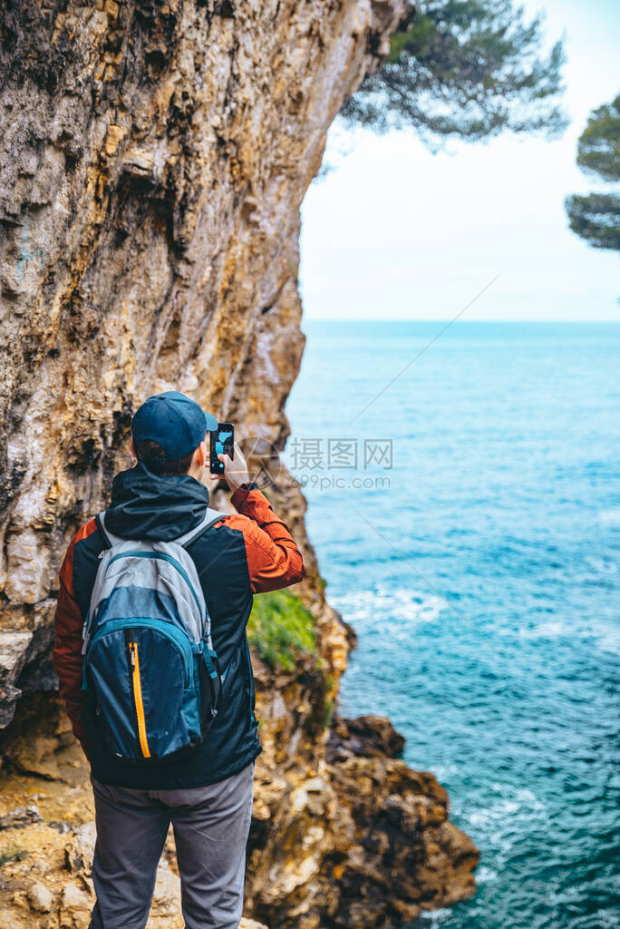 人类从悬崖上拍摄海的电话照片徒步旅行的概念图片