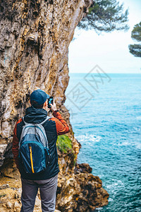 人类从悬崖上拍摄海的电话照片徒步旅行的概念图片