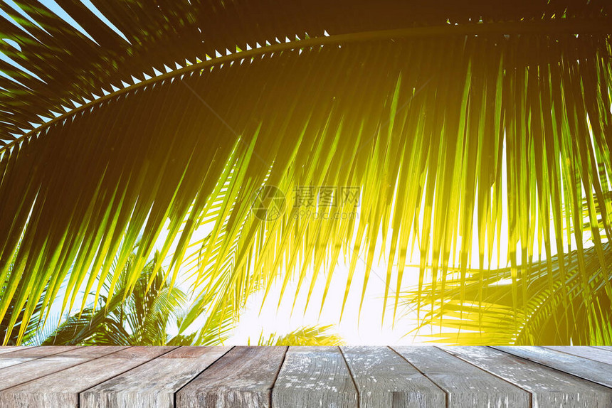 配有带浅渗漏背景的椰子叶的木质桌图片