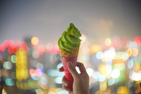 软焦点手拿着甜美的抹茶绿冰淇淋和脆的圆锥体图片