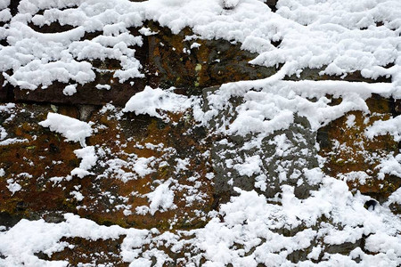岩石背景上的白雪和绿色苔藓图片