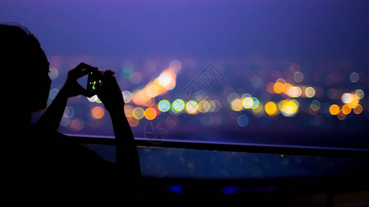 Silhouette年轻女子用智能手机拍摄照片图片