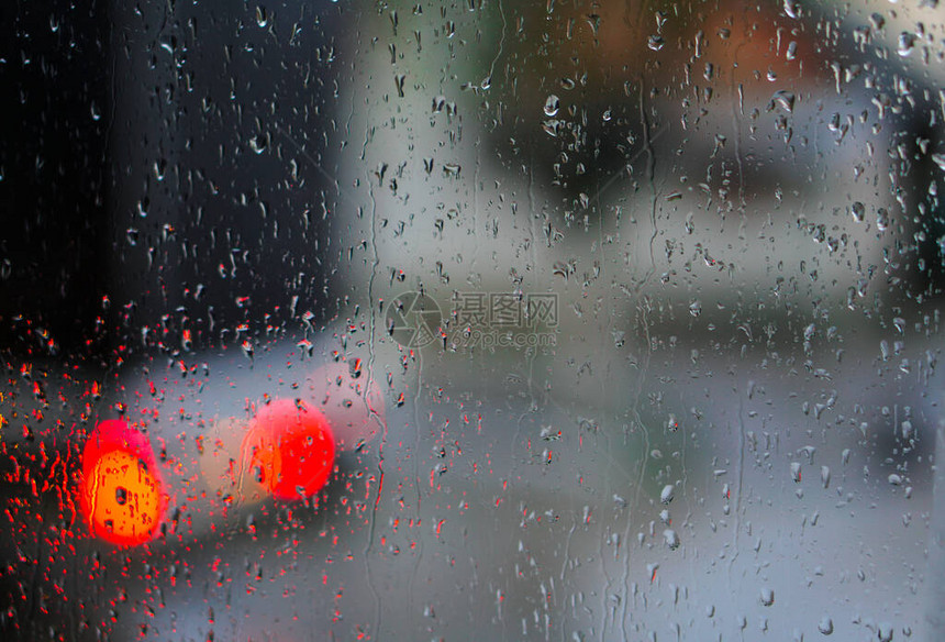 望向雨下街道的窗口路面明亮的夜晚天气汽车玻璃上的滴水和汽车上的bokeh图片