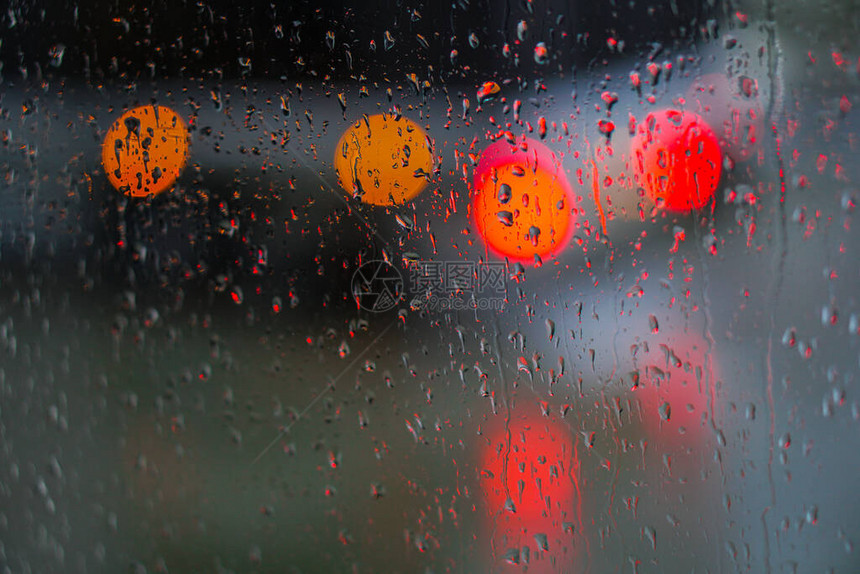 望向雨下街道的窗口路面明亮的夜晚天气汽车玻璃上的滴水和汽车上的bokeh图片