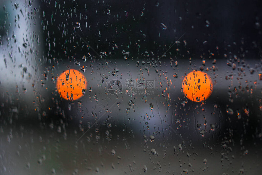 望向雨下街道的窗口路面明亮的夜晚天气汽车玻璃上的滴水和汽车上的bokeh图片