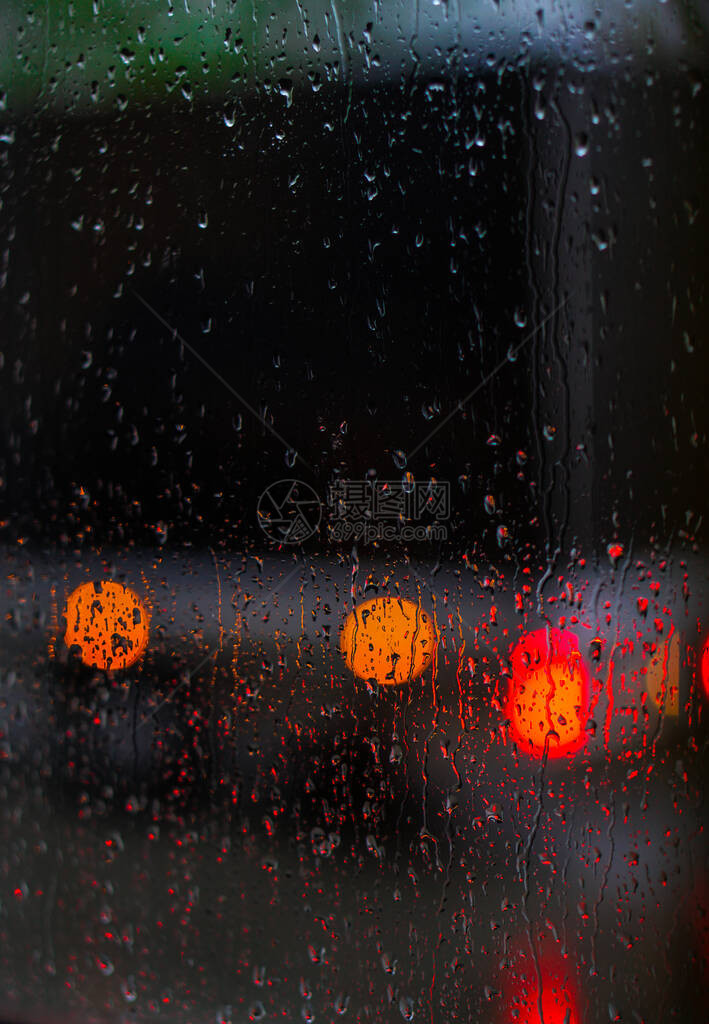 望向雨下街道的窗口路面明亮的夜晚天气汽车玻璃上的滴水和汽车上的bokeh图片