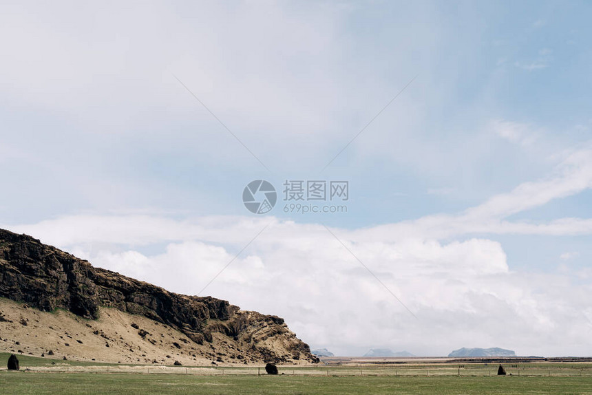 在冰岛岩石山和白云笼罩的蓝天空的背景下图片