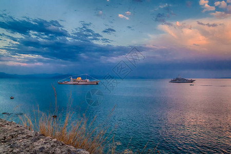 从希腊科孚岛堡垒的日落时看海景和游轮图片