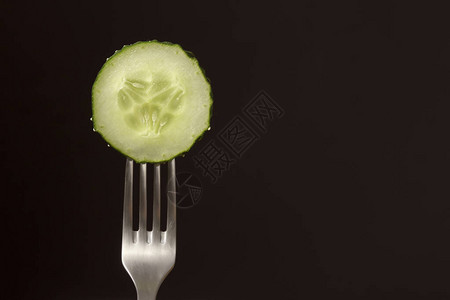 黑背景的叉子上新鲜绿黄瓜切片图片