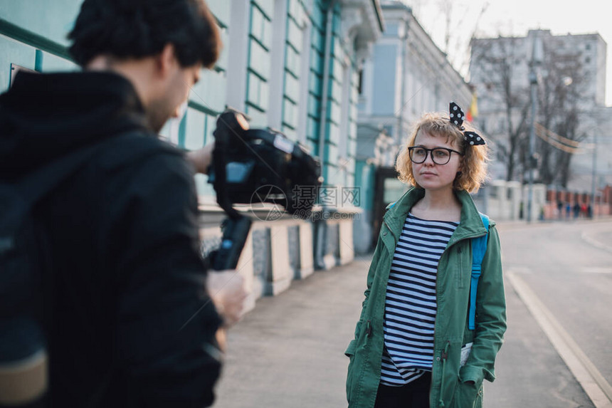 一个女孩在街上与一位摄影师制作视频博客年轻女博主记者用专业相机图片