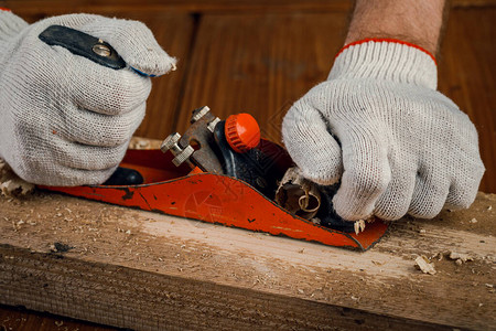 一位从事木工的木匠在他的车间里用手刨平木板的表面维修图片