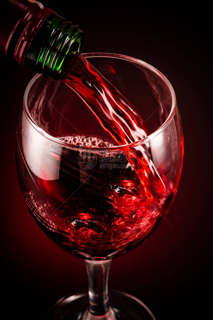 黑色背景中的一杯红酒和瓶子图片