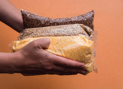 荞麦粥玉米粥小麦早餐煮粥的原料谷物成分将包装拿在手中背景图片