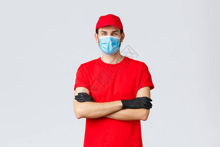 自信的笑脸送货员穿着红色帽子T恤衫佩戴保护医疗面具和橡皮手套图片