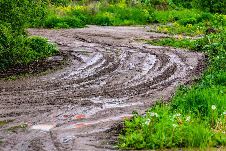带水坑和轮胎足迹的泥土路Zigzag转弯图片