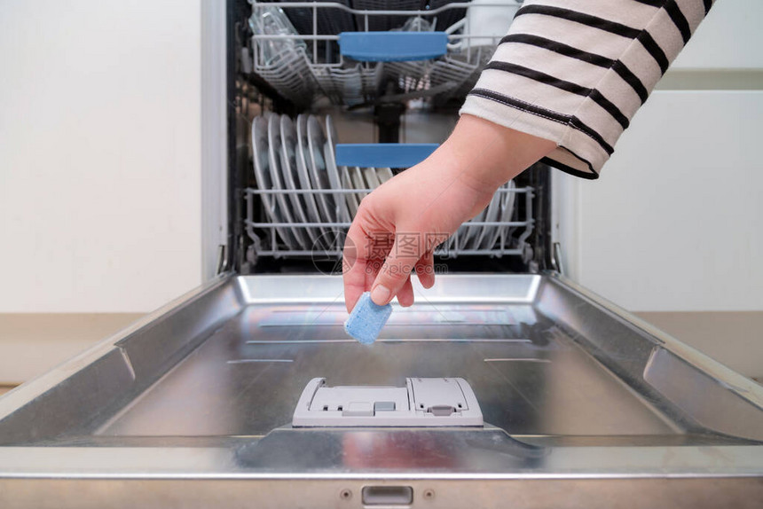 关闭将肥皂胶囊插入厨房洗碗机的手将洗碗精图片