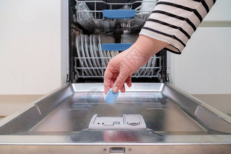 关闭将肥皂胶囊插入厨房洗碗机的手将洗碗精图片
