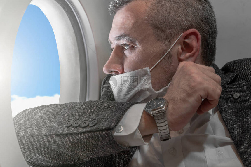 一名男子看着飞机的前哨身着夹克和面具的图片