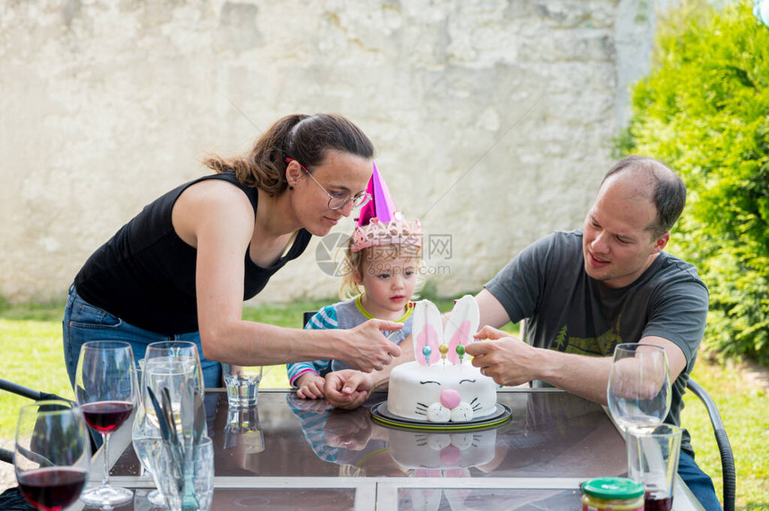 金发美女和爸妈一起庆祝生日家庭节日在户外兔子蛋糕上吹蜡烛图片