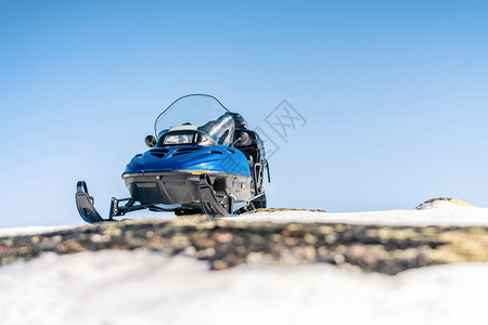 一辆蓝色的雪地摩托站在雪地上图片