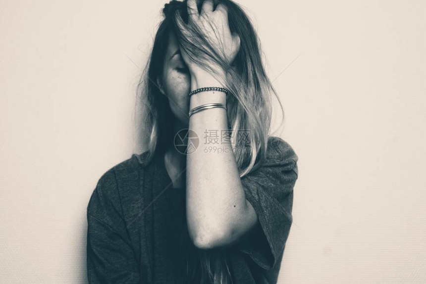 金发女孩用左手捂住脸黑白色图像描述悲伤担心沮丧的情绪图片